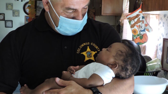 Dep. Devalle makes friends with the infant he and Sgt. Floyd saved Tuesday.