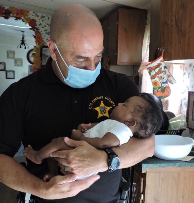 Dep. Devalle makes friends with the infant he and Sgt. Floyd saved Tuesday.