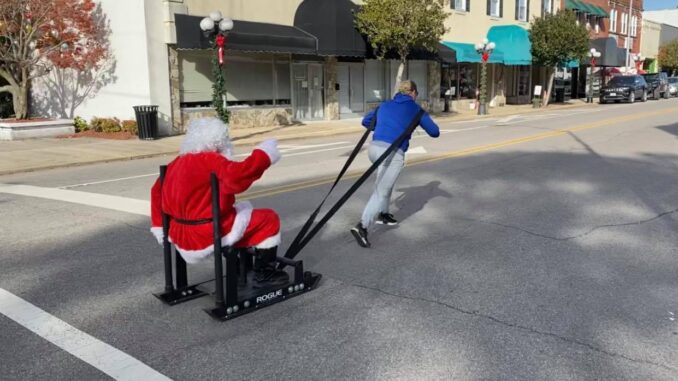 A woman pulling a sleigh where Santa Claus seats