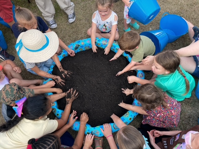 Under the direction of Lisa Yemma, the fledgling yam farmers mix their dirt prior to planting their yams.