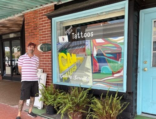 Christopher Gower in front of his art gallery and tattoo parlor.