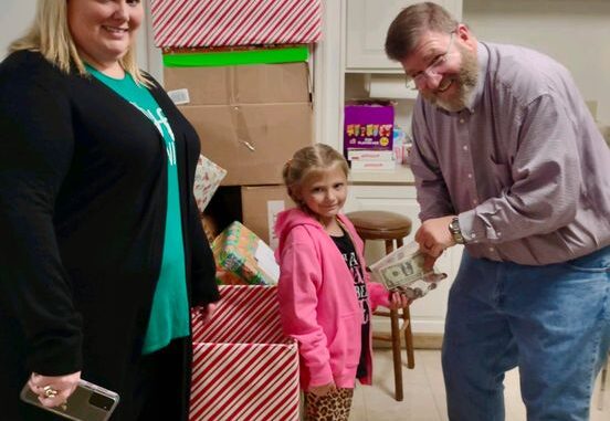 Dave Heller accepts Paisley Stevens' donation of $85 for the CBA Toy Store. Paisley's mother, Ash-Leigh Hewitt Stevens, thought Paisley was saving up for an iPhone.