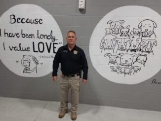 Sheriff Jody Greene with two of the new murals at the shelter. The murals are just some of the improvements that have been made at the shelter.