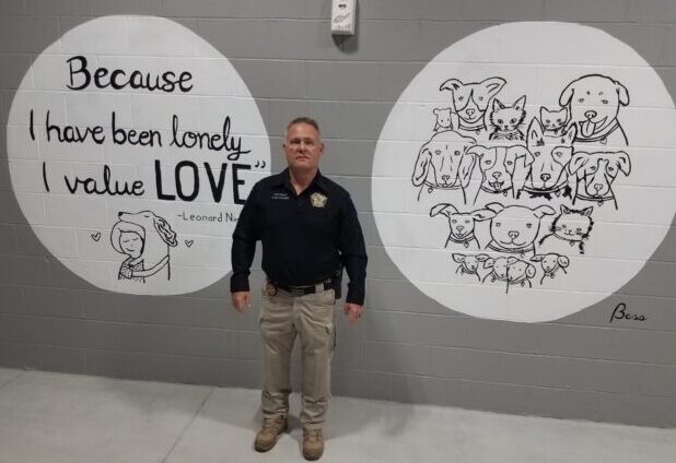 Sheriff Jody Greene with two of the new murals at the shelter. The murals are just some of the improvements that have been made at the shelter.