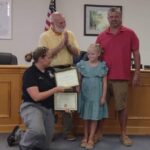 Fire and Rescue Chief Brandy Nance presents a Hometown Hero award to Jean-Aubry Williamson and her dad, Walt, while Commissioner Terry Littrell