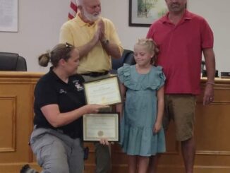 Fire and Rescue Chief Brandy Nance presents a Hometown Hero award to Jean-Aubry Williamson and her dad, Walt, while Commissioner Terry Littrell