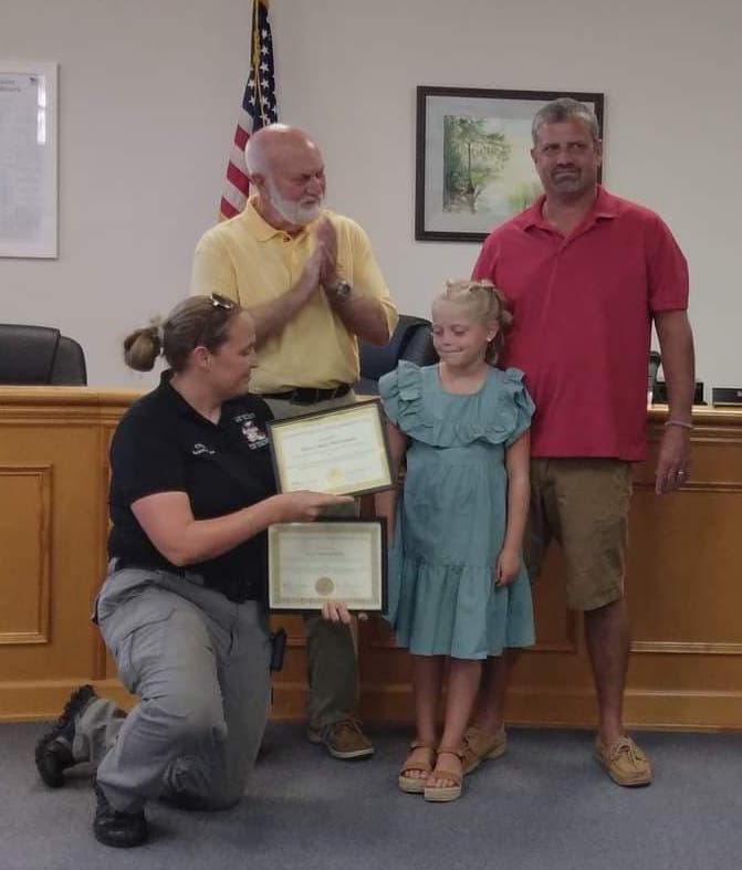 Fire and Rescue Chief Brandy Nance presents a Hometown Hero award to Jean-Aubry Williamson and her dad, Walt, while Commissioner Terry Littrell