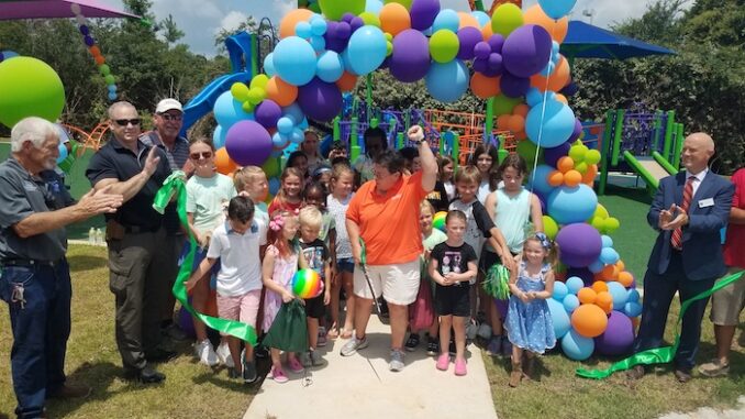 County Parks and Rec Director Julie Strickland cuts the ribbon officially opening the Trillium Play Area, with a little help from some of her closest friends.