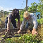 Columbus County Partnership for Children’s Outreach Coordinator Shaq Davis pulls weeds from a garden bed with Michael Shuman, extension technician of agriculture for the Columbus County Cooperative Extension.