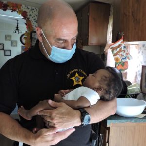Dep. Devalle makes friends with the infant he and Sgt. Floyd saved Tuesday.